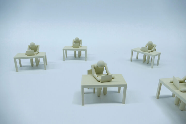 MaxGruber-Plastic figures resembling humans who sit at tables in front of laptops. the lack of background makes their envoronment look bleak.